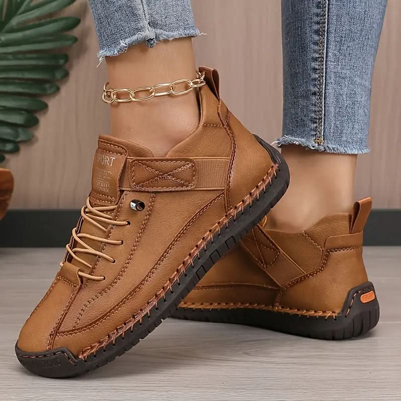 Brown stitched sneakers with strap, shown on feet with jeans and gold anklet
