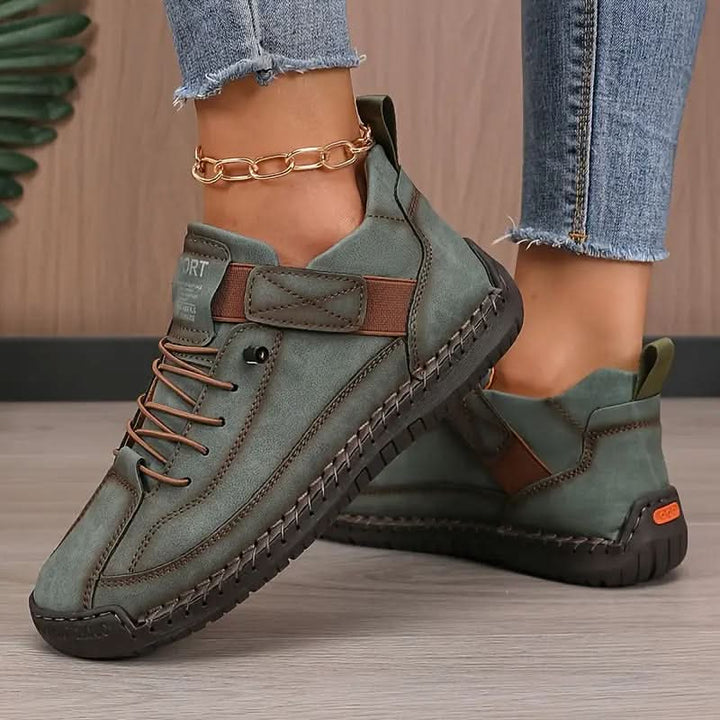 Khaki stitched sneaker with strap, worn on feet with jeans and gold anklet