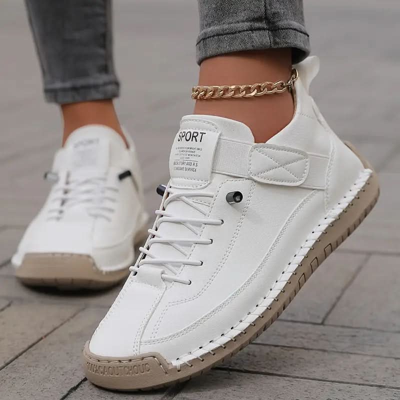White sneakers with strap and elastic laces, worn on a sidewalk with jeans