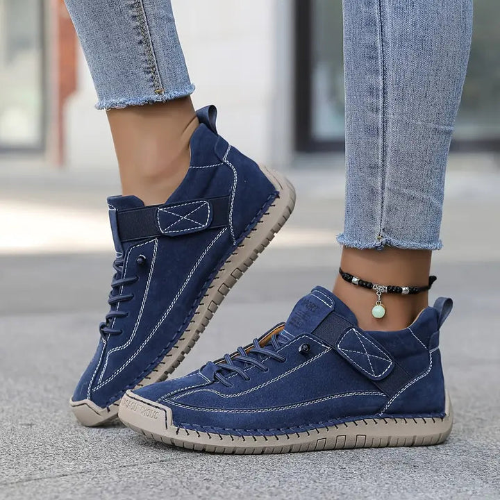 Navy stitched sneakers with strap, worn with frayed jeans and a beaded anklet