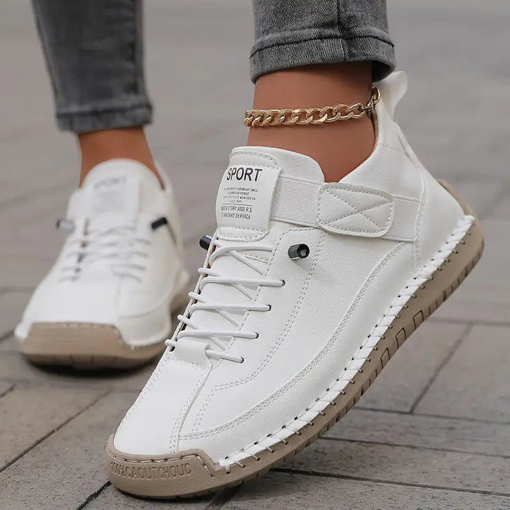 White sneakers with strap and elastic laces, worn with cuffed jeans and gold anklet