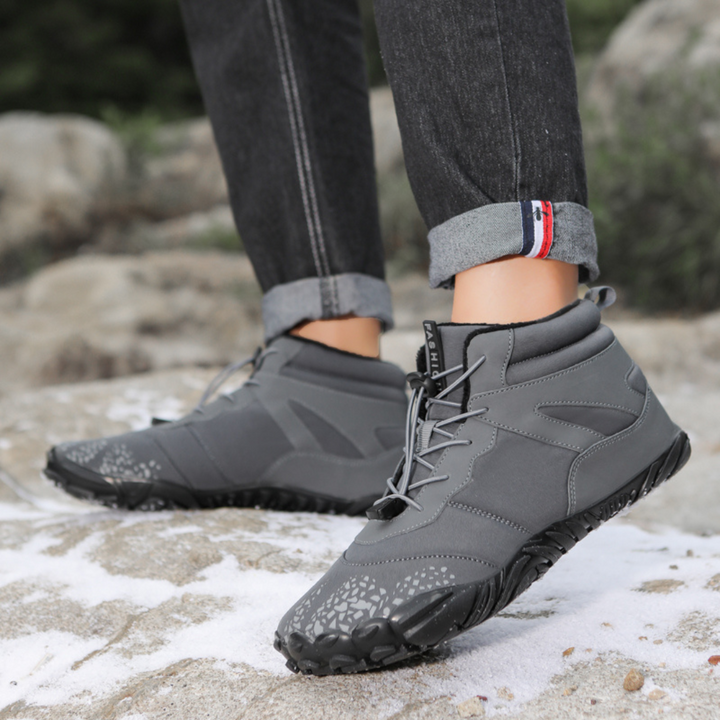 Gray lace up ankle boots worn on rocky snowy terrain with cuffed jeans