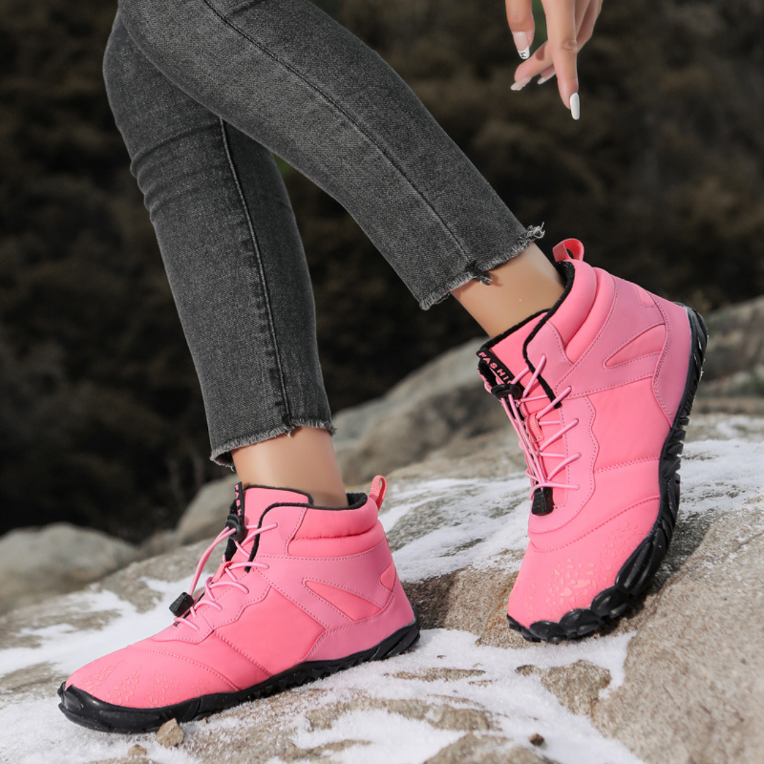 Pink wide toe boots worn mid-step on a rocky trail with cuffed jeans