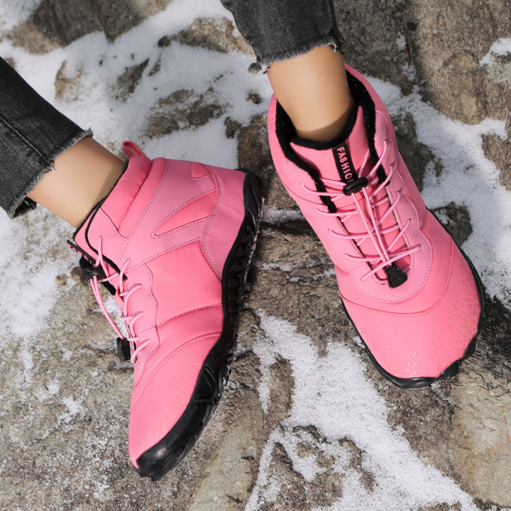 Pink lace up ankle boots worn on snowy rocks with gray jeans