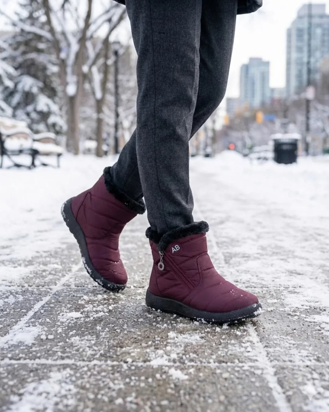 Burgundy ankle boots with faux fur cuffs walking on a snowy city path
