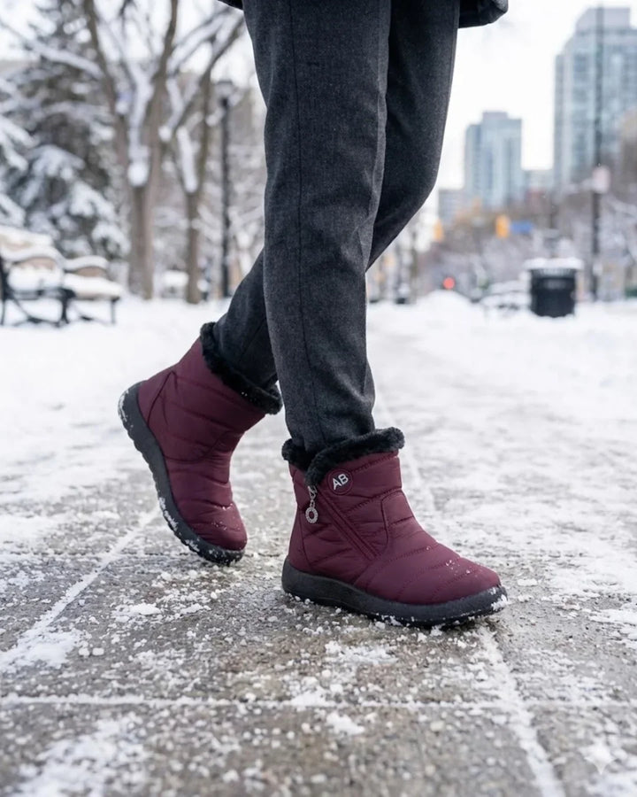 Burgundy ankle boots with faux fur cuffs walking on a snowy city path