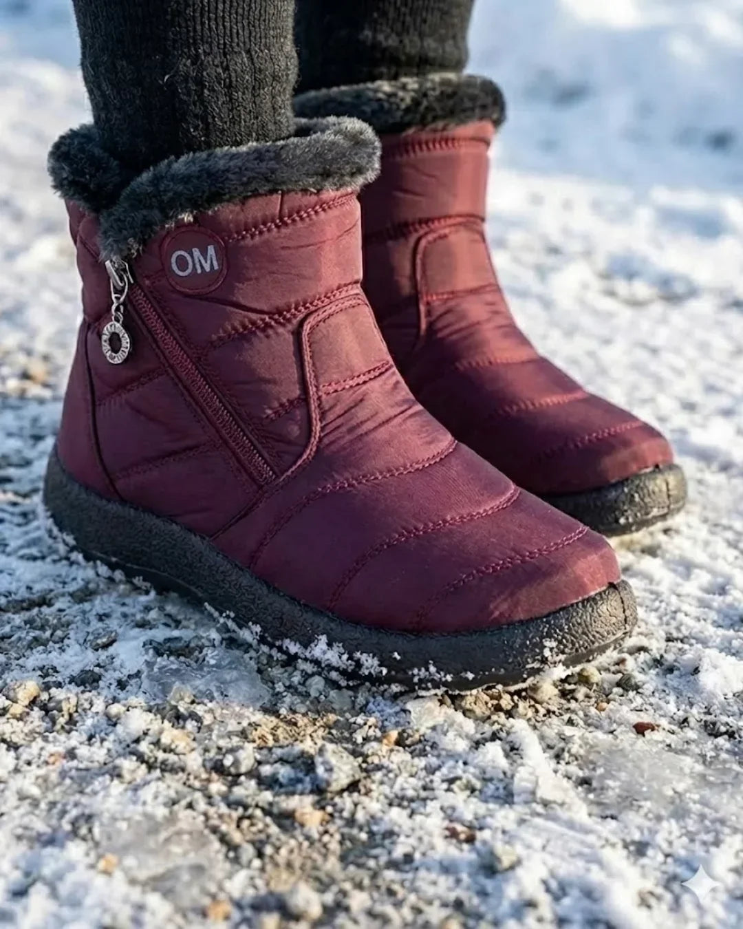 Burgundy ankle boots with fur trim worn on an icy path