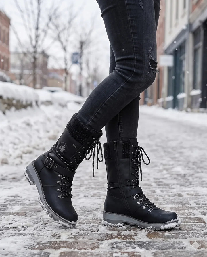 Woman walking in black lace up hiking boots on a snowy brick sidewalk