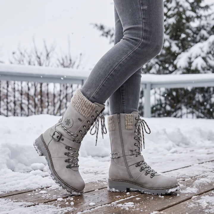 Gray lace up boots with knit cuff worn outdoors on a snowy wooden deck