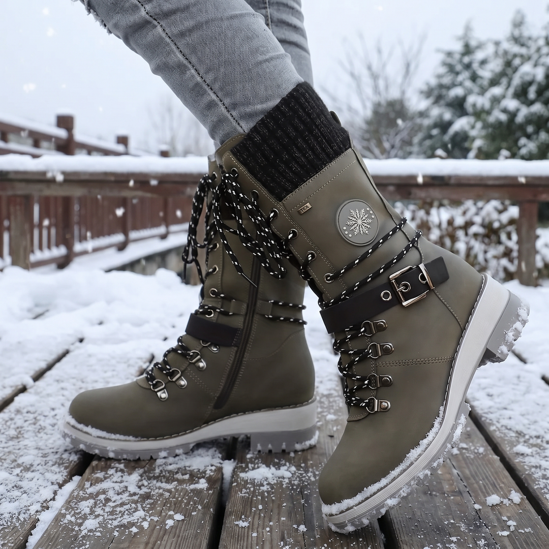 Olive lace up hiking style boots worn in the snow with ankle buckle visible