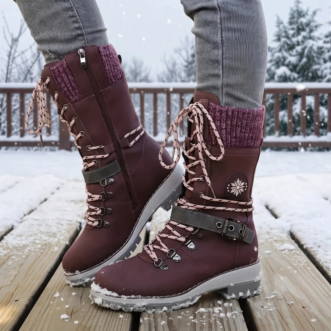 Plum lace up boots with pink laces worn on snowy wooden planks