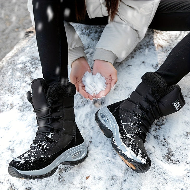 Black platform boots on snow with a hand holding a snowball