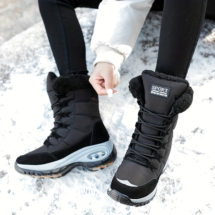 Black lace up boots on snow while the wearer pulls the laces tight