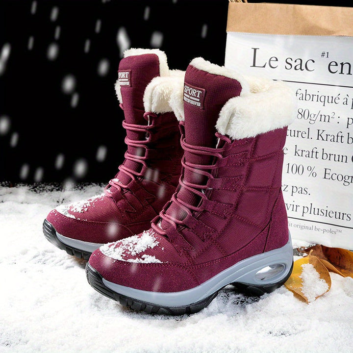 Pair of burgundy mid calf boots with plush collars standing in the snow