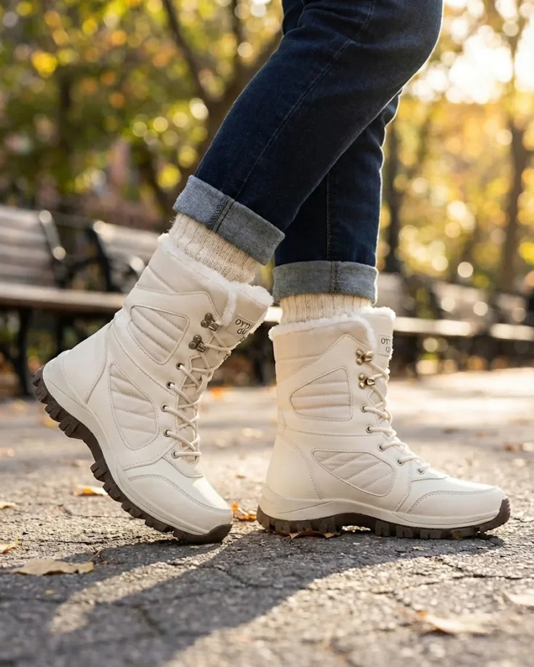 Cream fur trimmed boots worn with rolled jeans on a sunny park path
