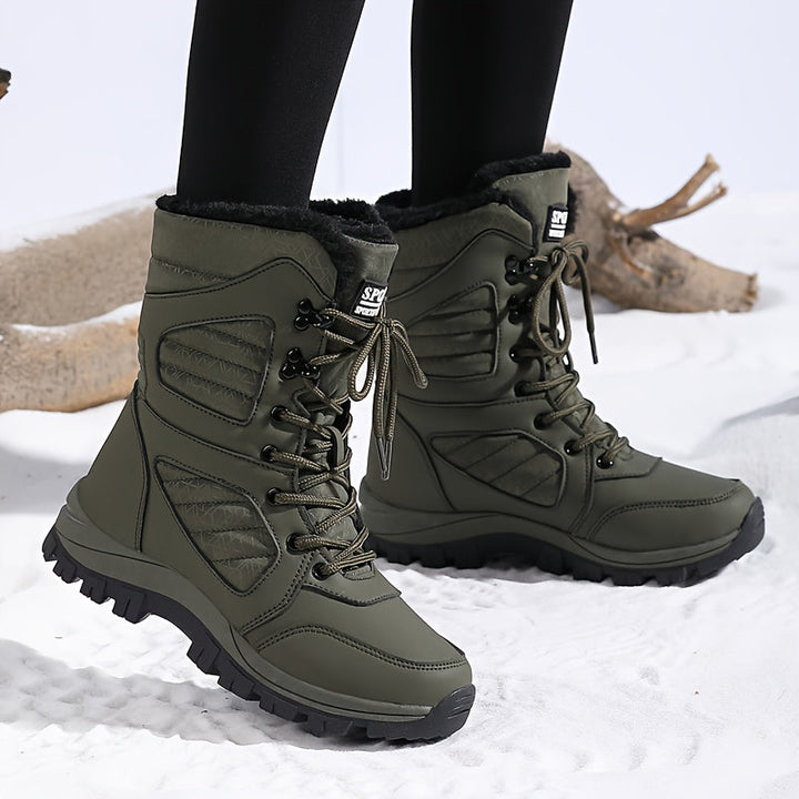Olive green lace up boots in a walking pose on snow
