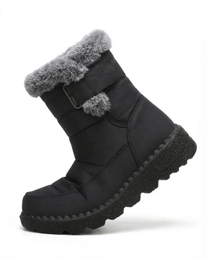 Black quilted boot angled to show the strap, pom-pom and faux fur trim
