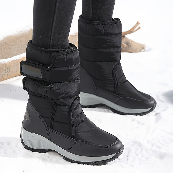 Black quilted mid calf boots worn with dark leggings in the snow