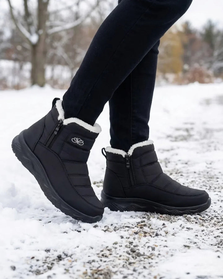 Black quilted ankle boots worn walking through snow with black pants