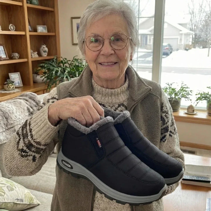 Smiling woman holding a pair of black quilted slip on ankle boots