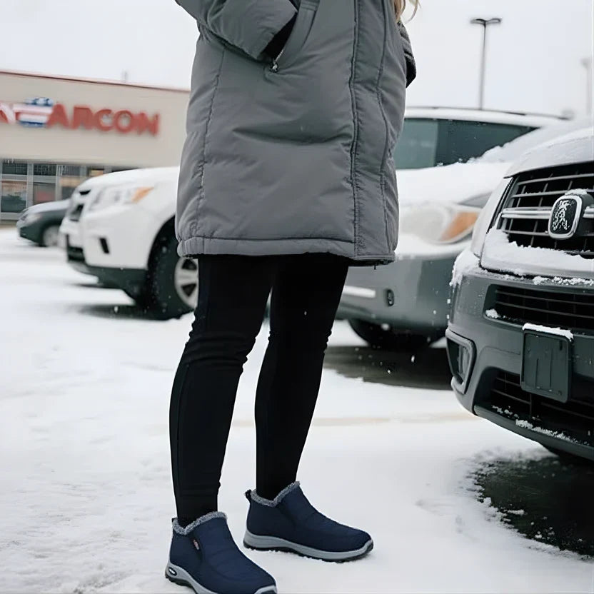 Navy quilted ankle boots worn with black leggings on a snowy parking lot