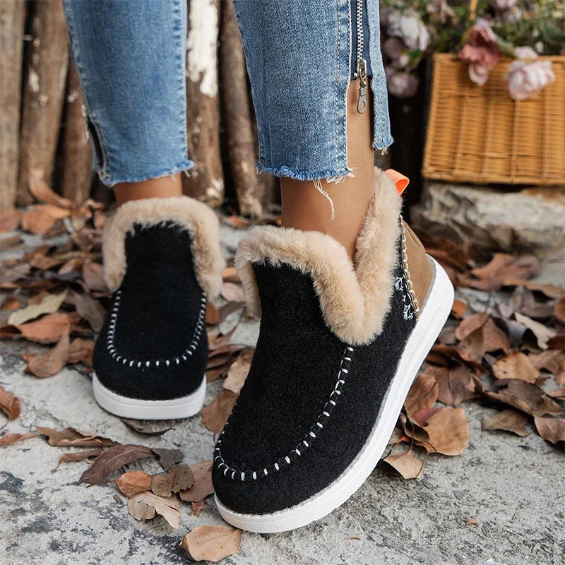 Black slip on ankle boots with faux fur trim worn with cuffed jeans on leaves