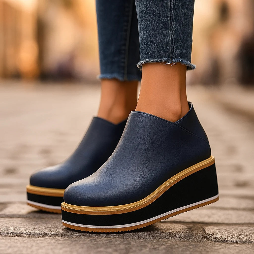 Navy platform wedge ankle boots worn with rolled jeans on a city street