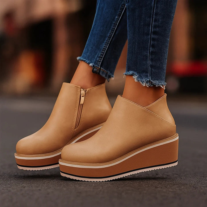 Tan platform wedge booties with side zip worn with cuffed jeans on a street