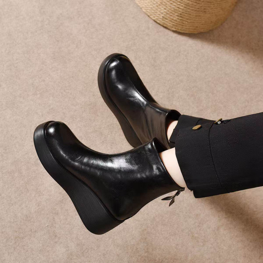Black platform wedge ankle booties with back zip worn with black pants
