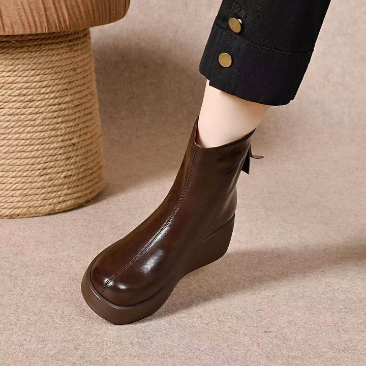 Brown platform wedge ankle boot with back zip worn with black pants