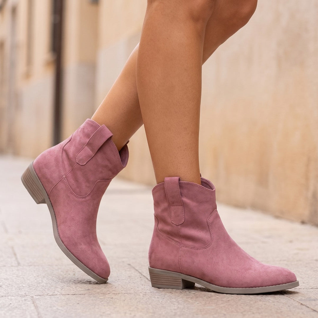 Pink western ankle boots worn on a sunlit pavement