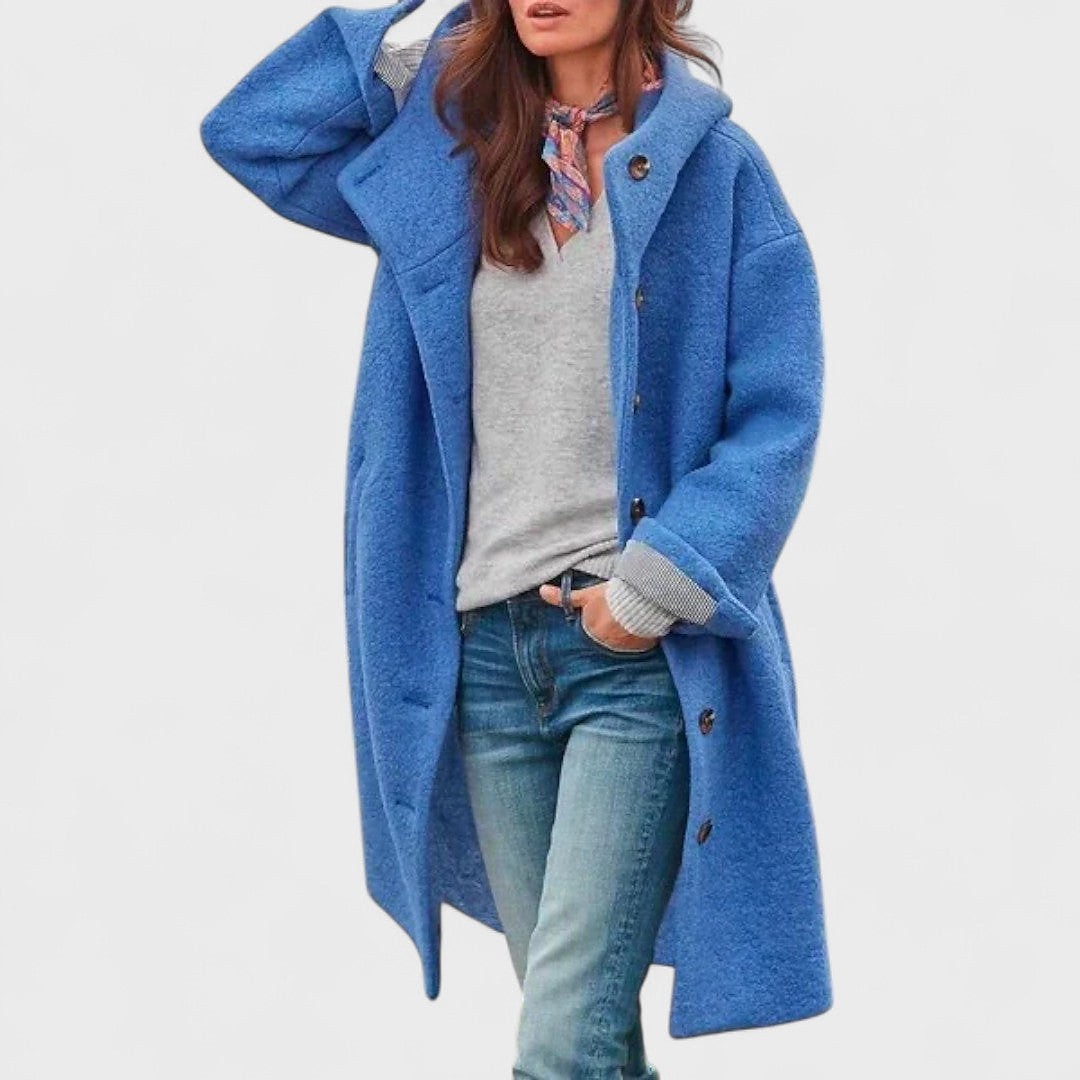 Blue long hooded coat worn open over a gray sweater and denim