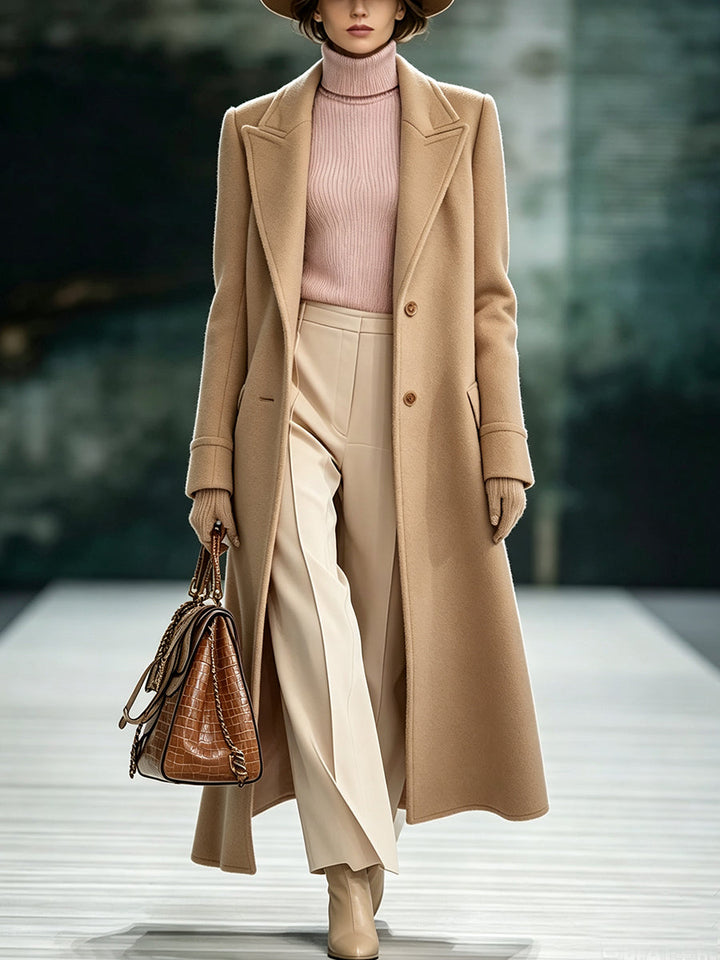 Camel long tailored coat worn over a pink turtleneck and cream wide-leg pants