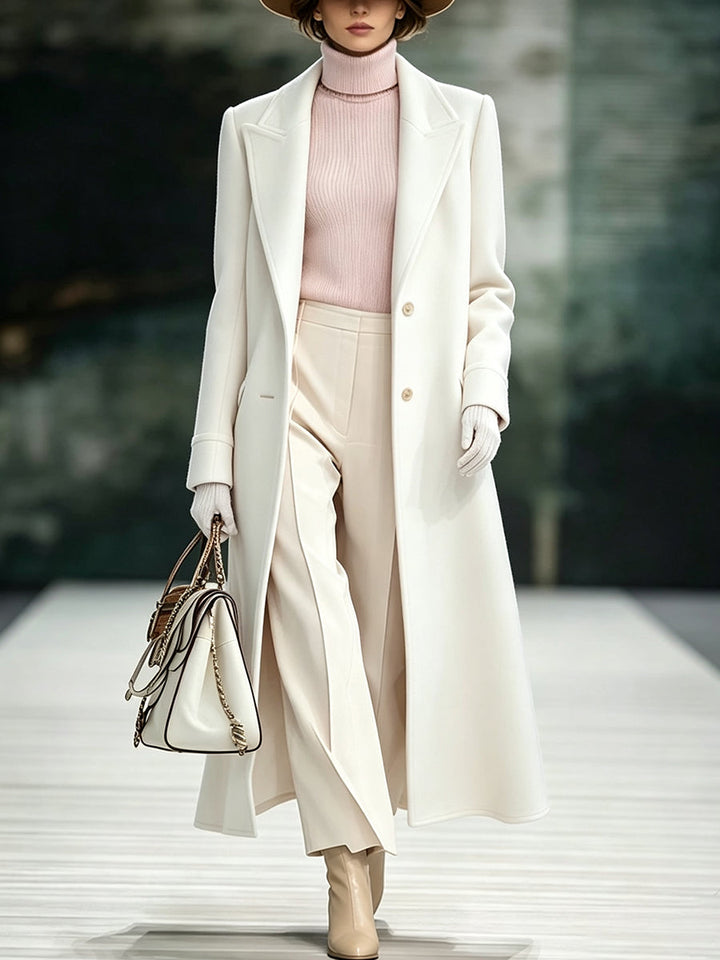 Ivory long coat with sharp lapels, styled with a white structured handbag