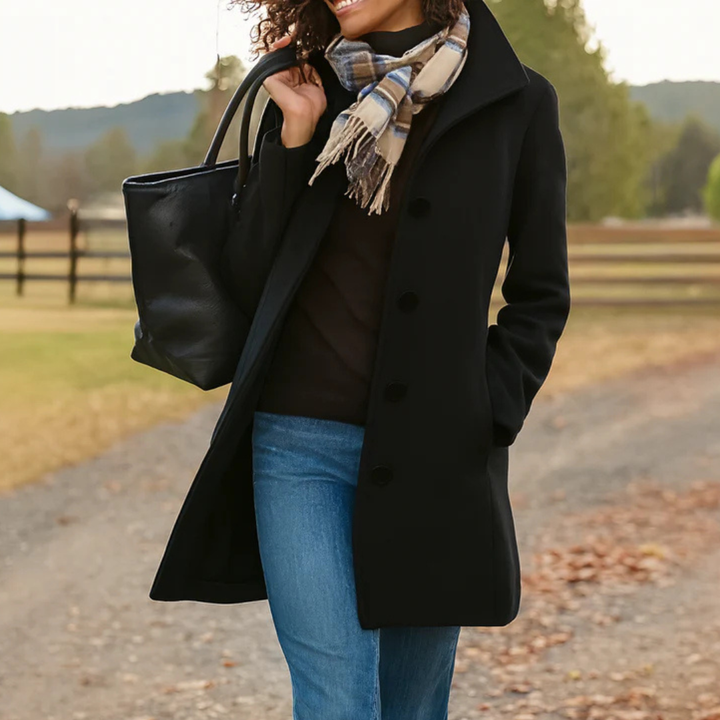Black mid length winter coat with button front and plaid scarf outdoors