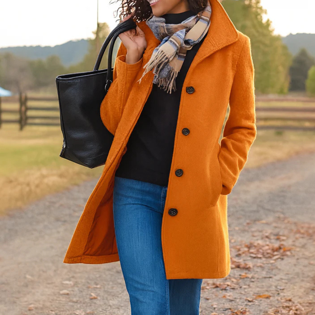 Orange mid length coat with collar, styled with jeans and black tote