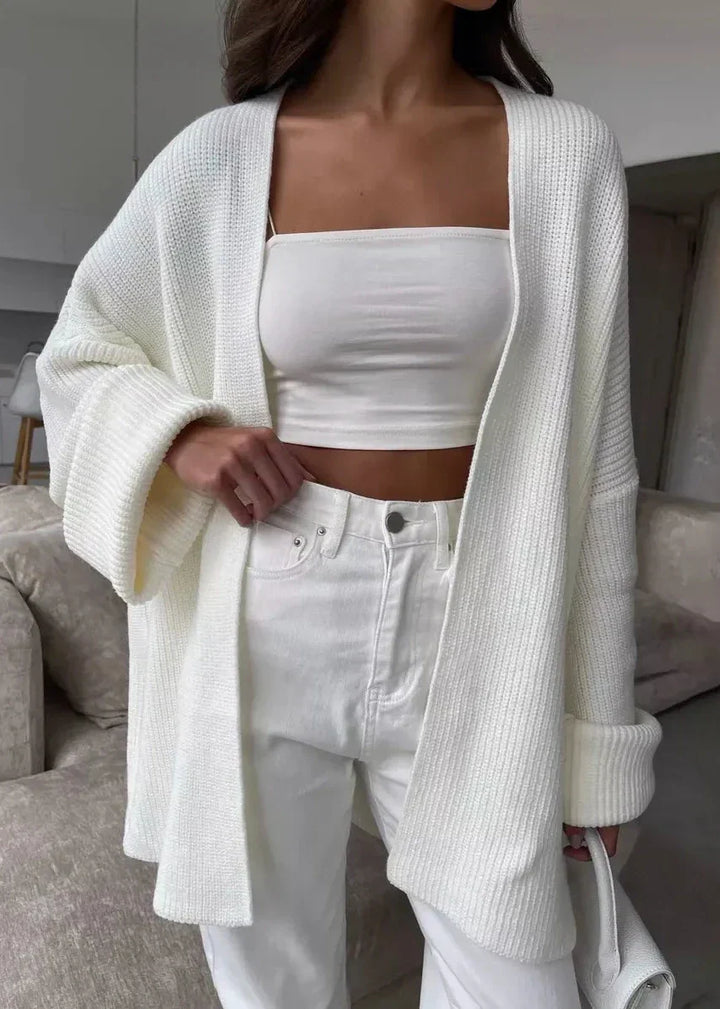 Ivory cardigan worn open over a white bandeau top and straight pants