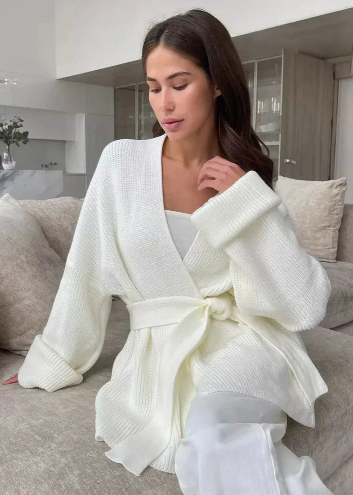 Woman seated on a sofa in the ivory belted cardigan