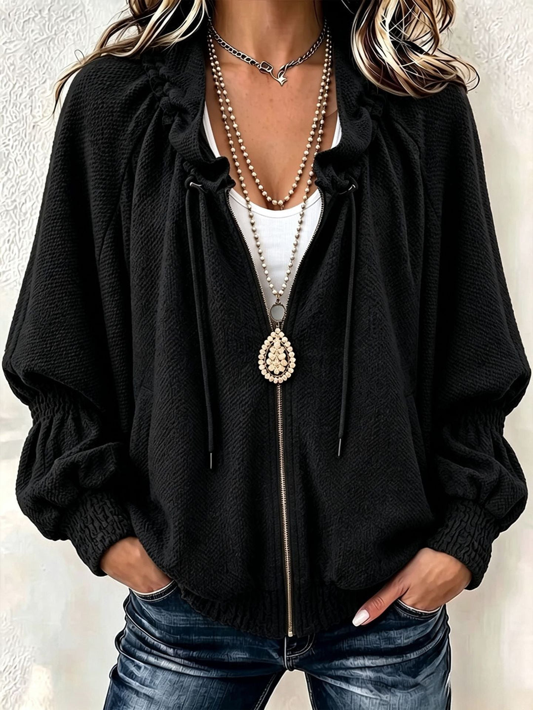 Black batwing jacket with full-length zip, styled with dark denim